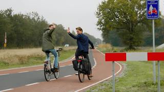 Twee fietsers op fietspad zwaaien.
