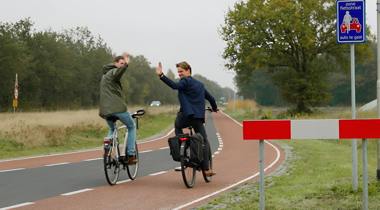 Twee fietsers op fietspad zwaaien.