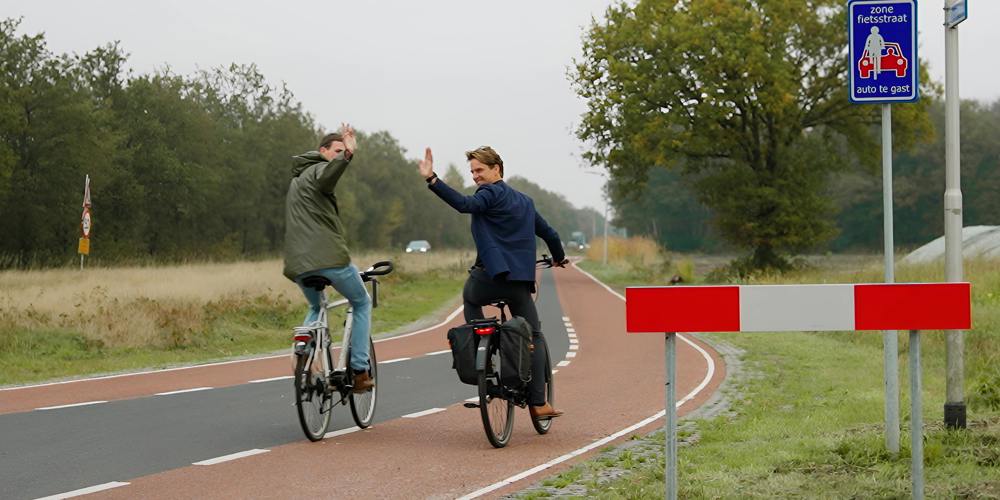 Twee fietsers op fietspad zwaaien.