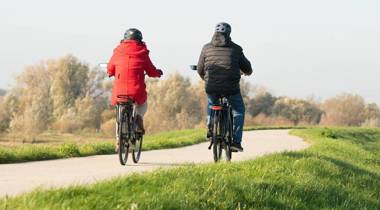Twee mensen fietsen op een pad door een groen landschap.