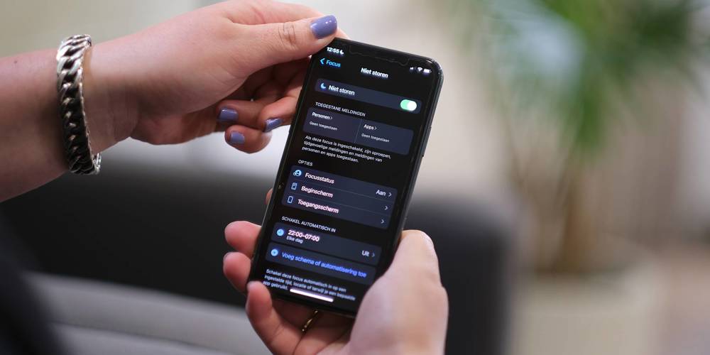 Een close-up van een persoon die een smartphone vasthoudt. Het scherm toont de instellingen van de Focus-modus (Niet storen), in het Nederlands.
