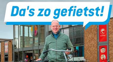 Man met fiets voor winkelcentrum, met tekstballon: Da's zo gefietst!
