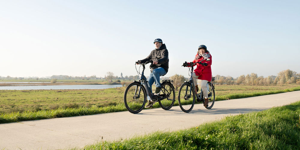 Een man en een vrouw op een fiets met een fietshelm op