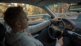 Jongeman in grijze hoodie rijdt in BMW. Fotograaf Sol Jansson - Unsplash