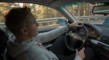 Jongeman in grijze hoodie rijdt in BMW. Fotograaf Sol Jansson - Unsplash