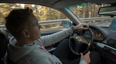 Jongeman in grijze hoodie rijdt in BMW. Fotograaf Sol Jansson - Unsplash
