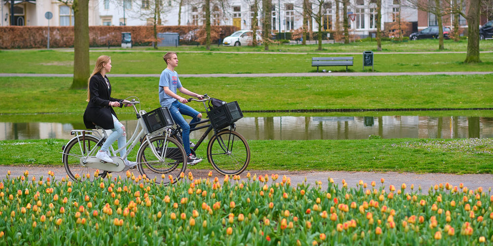 Twee mensen fietsend door een park met bloemen