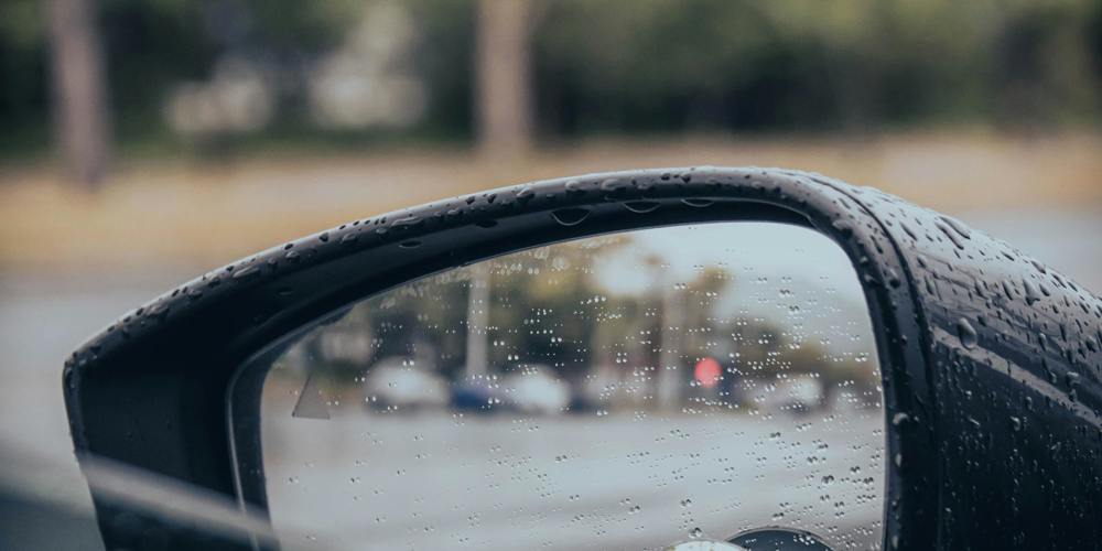 Foto door Jason Yuen van Unsplash - Beregende spiegel van een auto