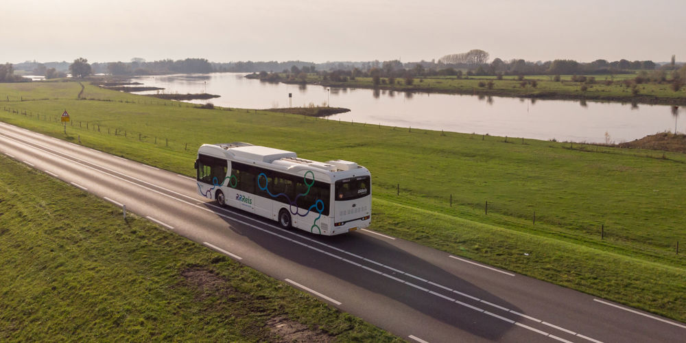 Bus op een verkeersweg tussen weilanden