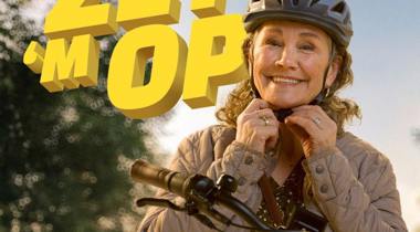 Een vrouw zet haar fietshelm op met de tekst 'ZET 'M OP' in beeld.