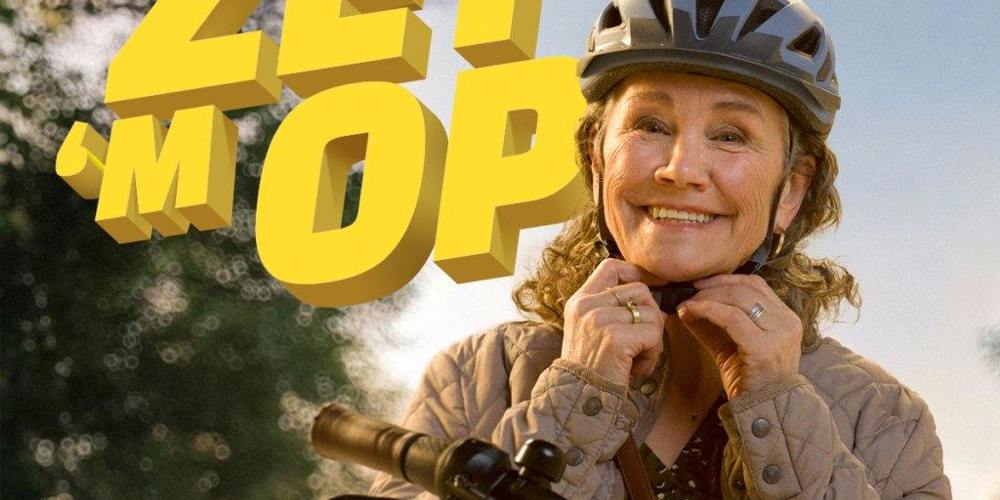 Een vrouw zet haar fietshelm op met de tekst 'ZET 'M OP' in beeld.