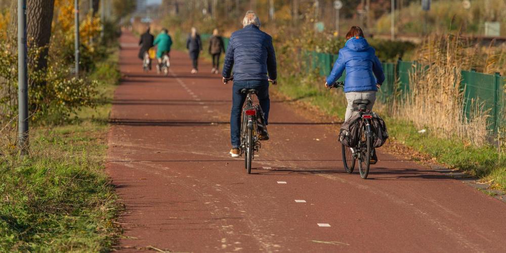 Fietsers en wandelaars op een fietspad F35 langs spoorlijn.