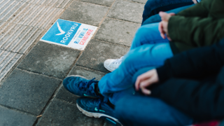 Groep mensen zittend bij rookvrije zone met tegeltekst 'ROOKVRIJ RUIMTE GEMEENTE'