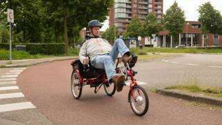 Man fietst op een driewieler over een fietspad in de stad.