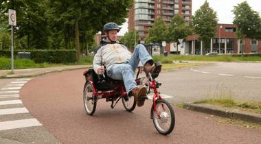Man fietst op een driewieler over een fietspad in de stad.