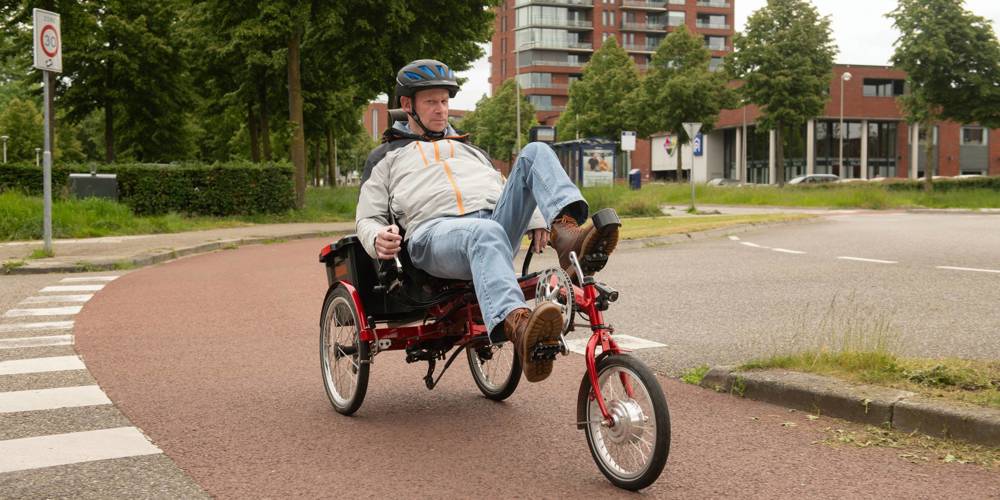 Man fietst op een driewieler over een fietspad in de stad.